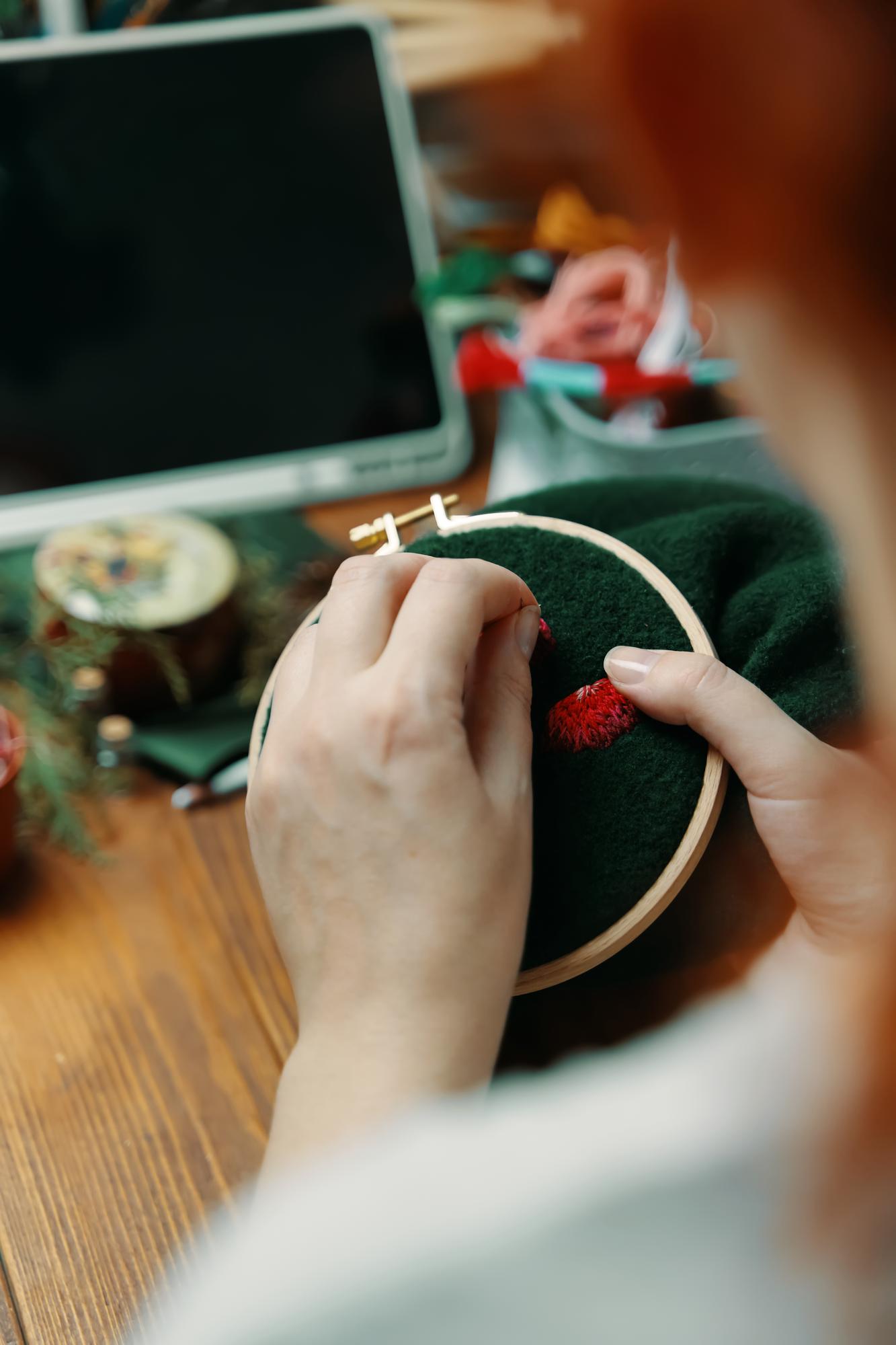 artisan hands stitching embroidery hoop in studio